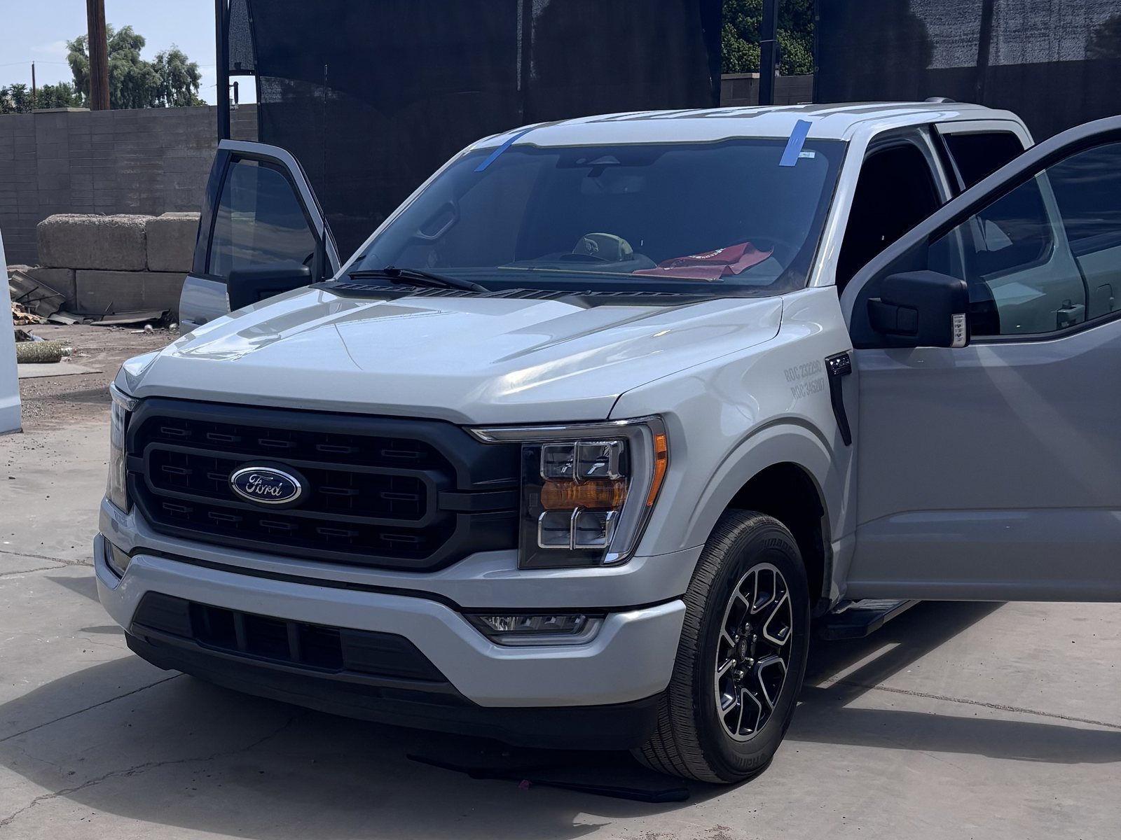 Ford pickup with a freshly set windshield, blue tape holding the glass while it cures